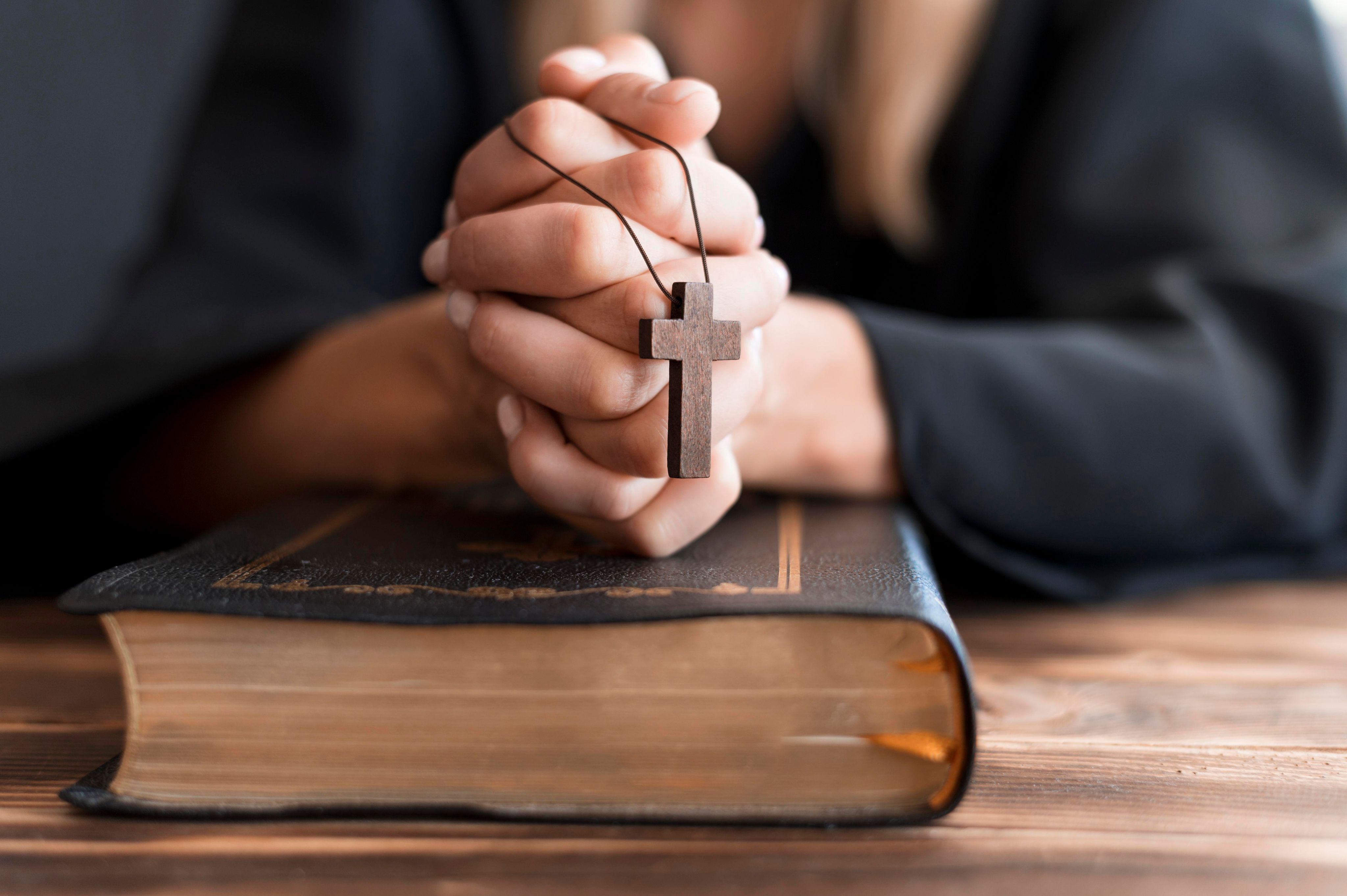 person-praying-with-cross-holy-book.jpg